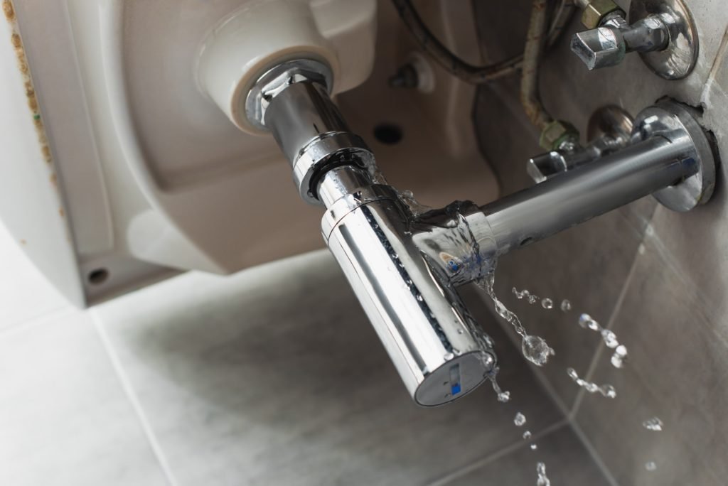 Leaking steel pipe under sink with water drops